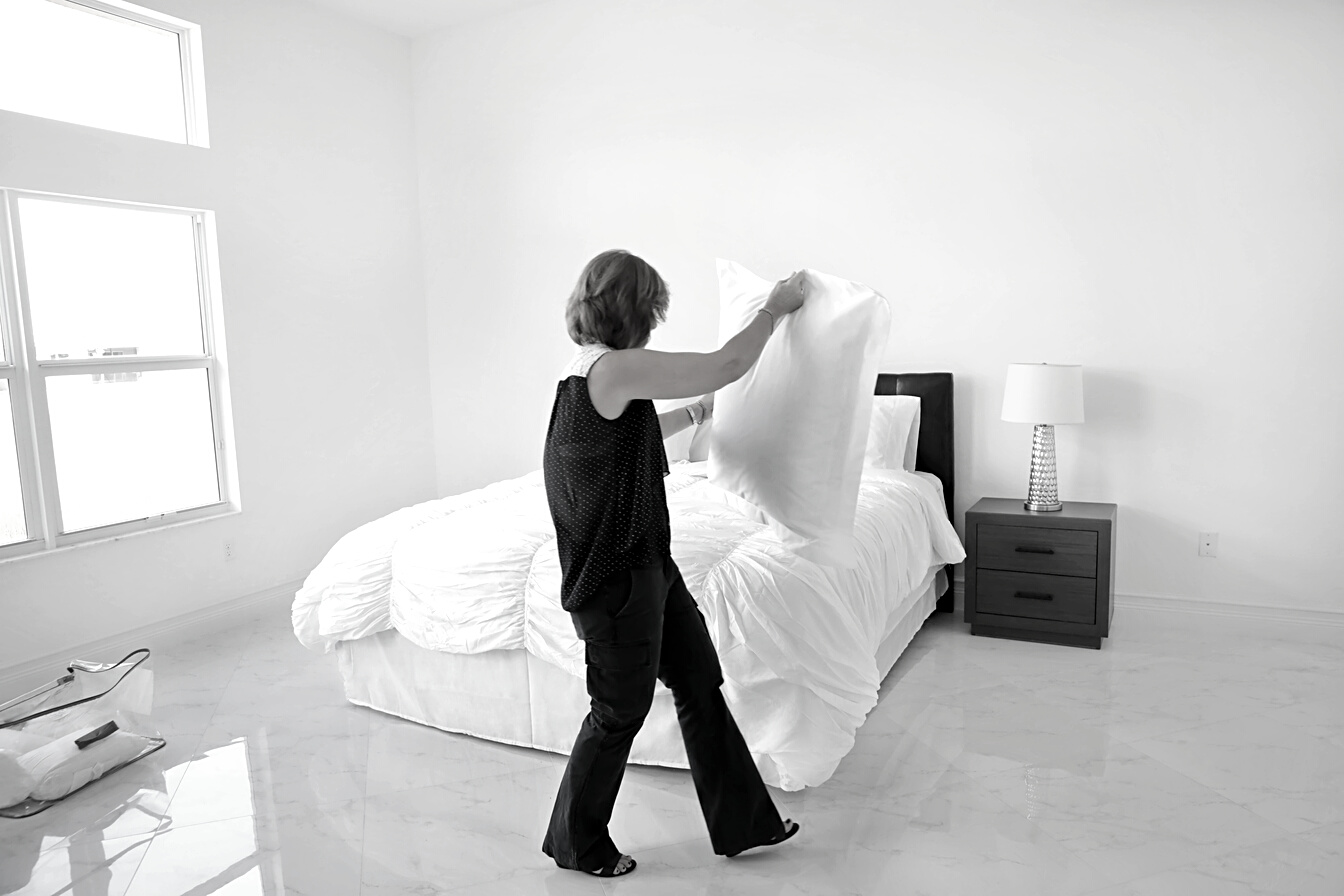 Series:House staging. Professional stager making bed in home for sale